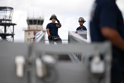 firefighter speaks to another firefighter while exiting an aerial apparatus.