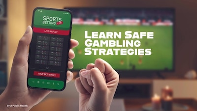 Hands holding cell phone open to "Sports Betting" app. TV in background showing football game says, "Learn Safe Gambling Strategies."