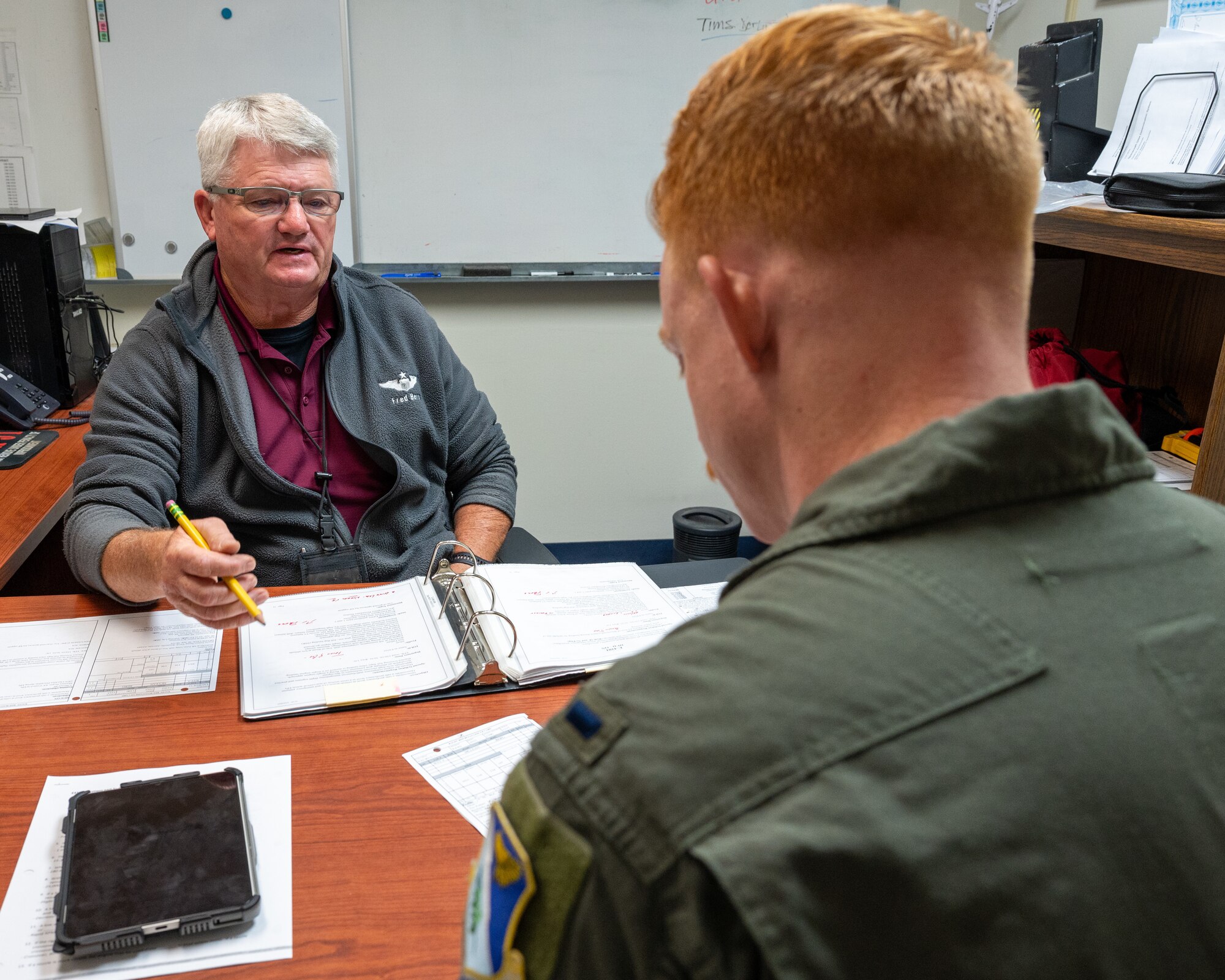 Frederick Berg, 47th Student Squadron (STUS) civilian simulator instructor, left, talks to U.S. Air Force 1st Lt. Thomas McLean, 47th STUS student pilot, right about his upcoming simulator flight at Laughlin Air Force Base, Texas, Sept. 3, 2025. Berg has spent 40 years in federal service teaching thousands of classes and has more than 15,000 hours in simulator flights. (U.S. Air Force photo by Staff Sgt. Nicholas Larsen)