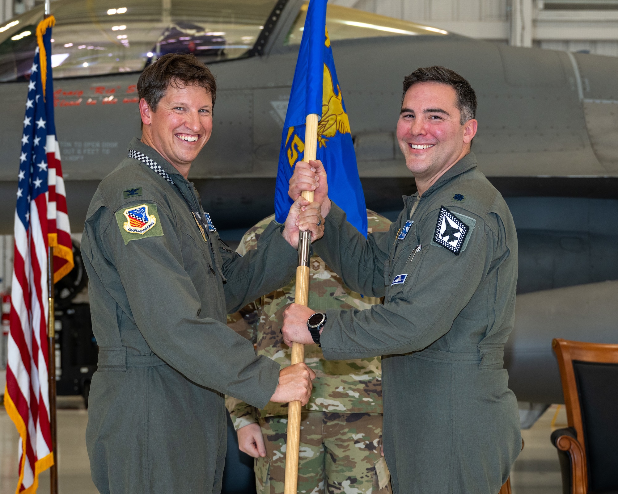 Col. Tavis Powell, 482d Fighter Wing deputy commander, passes the 482d Operations Support Squadron guidon to Lt. Col. Logan Brewer during an assumption of command ceremony at Homestead Air Reserve Base, Florida, Sept. 5, 2025. (U.S. Air Force photo by Master Sgt. Lionel Castellano)