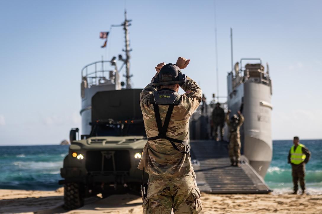 A U.S. Soldier with 7th Transportation Brigade ground guides a Joint Light Tactical Vehicle assigned to 3d Littoral Logistics Battalion (LLB), 3d Marine Littoral Regiment, 3d Marine Division, onto a Maneuver Support Vessel (Light) (MSV(L)) on Marine Corps Base Hawaii, Aug. 26, 2025. The purpose of this training was to test the interoperability between the Army’s MSV(L) and Marine Corps equipment, demonstrating the readiness of 3d LLB to adapt to interservice transportation. (U.S. Marine Corps photo by Sgt. Malia Sparks)