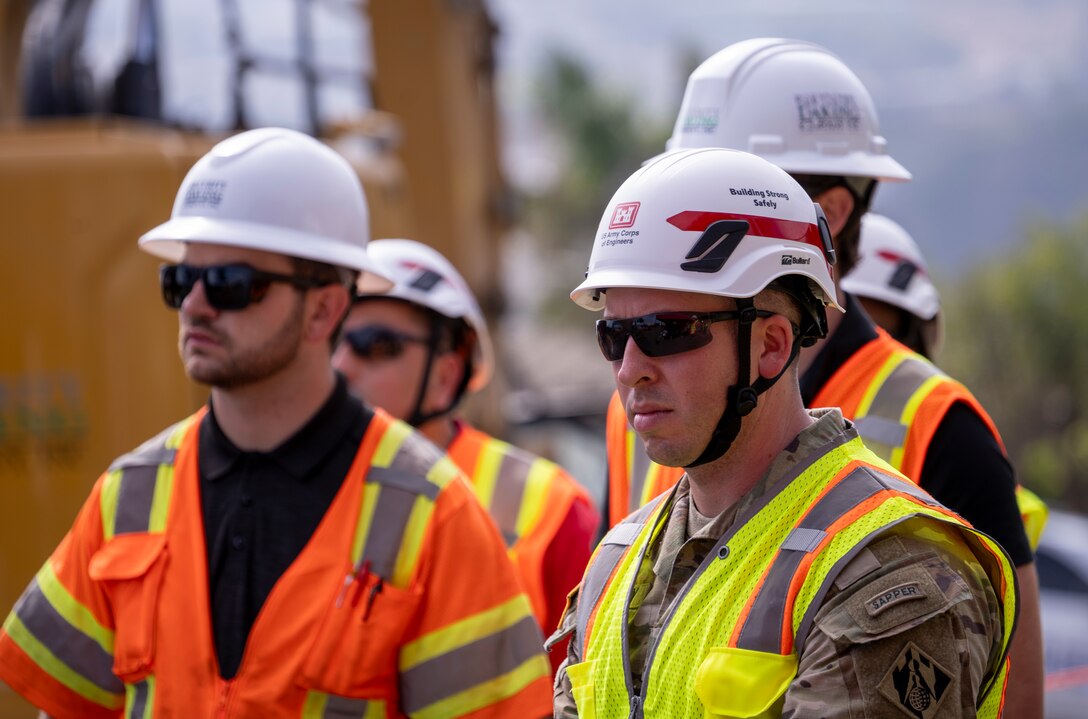 Members of the U.S. Army Corps of Engineers stand with contractors during the Aug. 26 milestone event marking the start of debris removal for the last opt-in private property in the Pacific Palisades fire recovery area in Los Angeles.