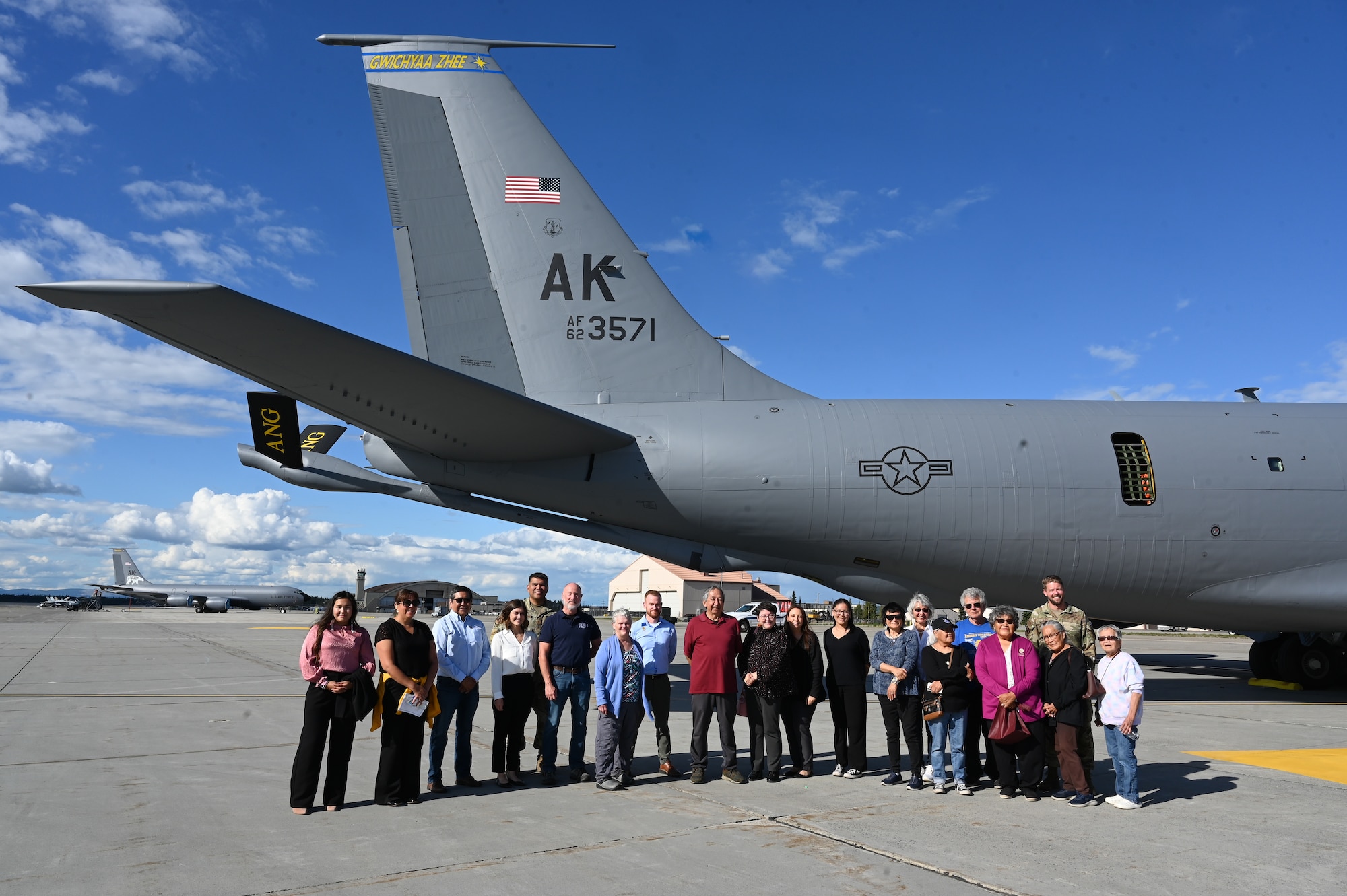 Representatives from the local Interior Alaska Villages pose for a photo in front of the Alaska Air National Guard Gwichyaa Zhee tail flash at Eielson Air Force Base.