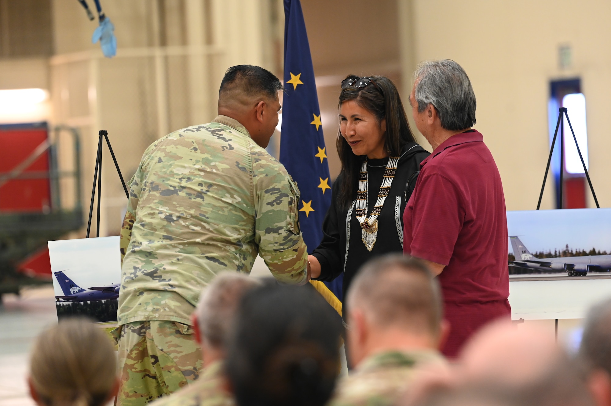 Master Sgt. Anthony Crisostomo shakes hands with the representatives from Tetlin while presenting them with a print of the Alaska Air National Guard KC-135.