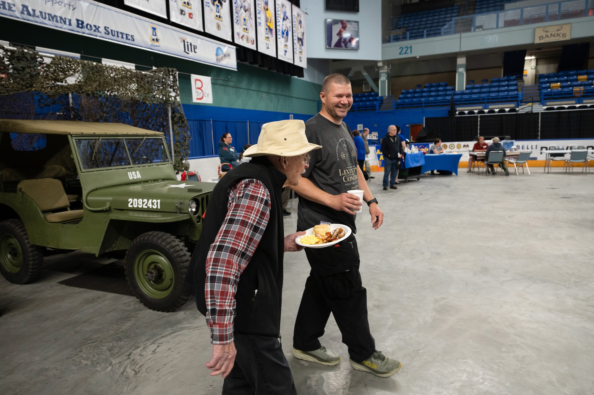 U.S. Air National Guard Senior Master Sgt. James Sjoblom of the 168th Maintenance Group helps a Veteran to his seat while volunteering during the 2025 Fairbanks Veterans Stand Down