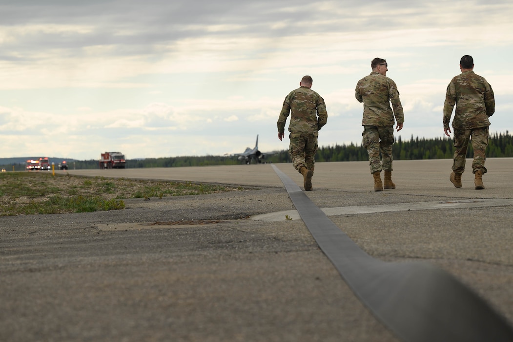 U.S. Air Force Senior Airman Joseph Stinson, left, and Staff Sgt. Troy Smith, center, 354th Civil Engineering Squadron power production journeymen, and Staff Sgt. Nathaniel Phillips, 354th CES power production barrier maintenance craftsman, check an Aircraft Arresting System cable during a system test at Eielson Air Force Base, Alaska, May 29, 2025.