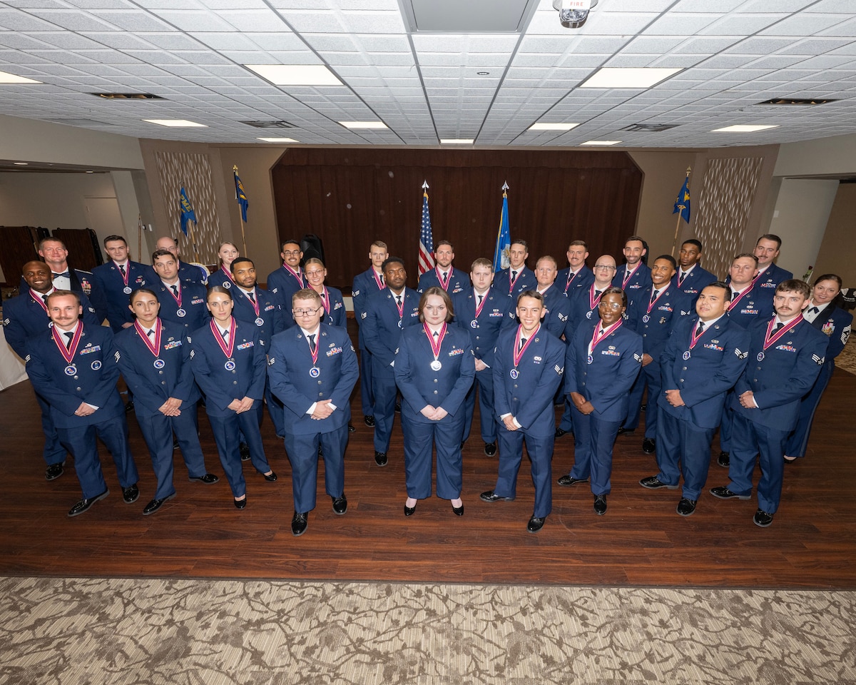 A group of Airmen in dress uniform pose for a photos