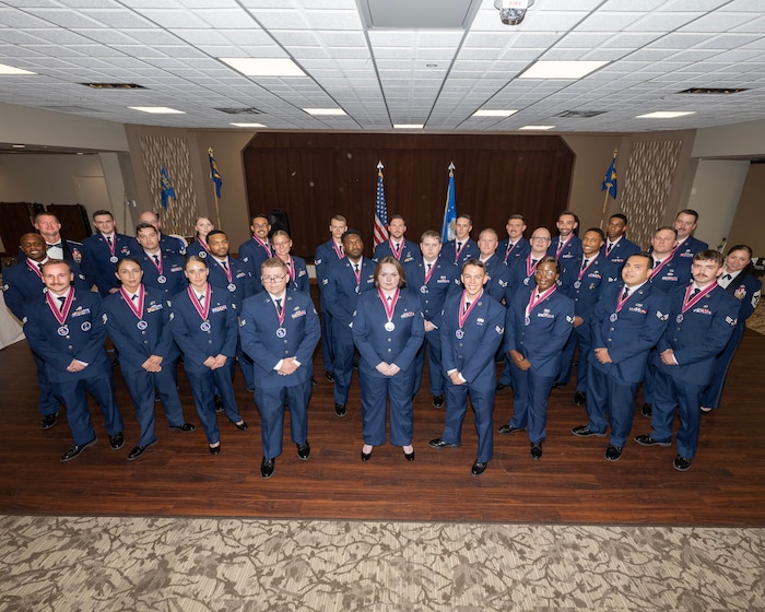 A group of Airmen in dress uniform pose for a photos