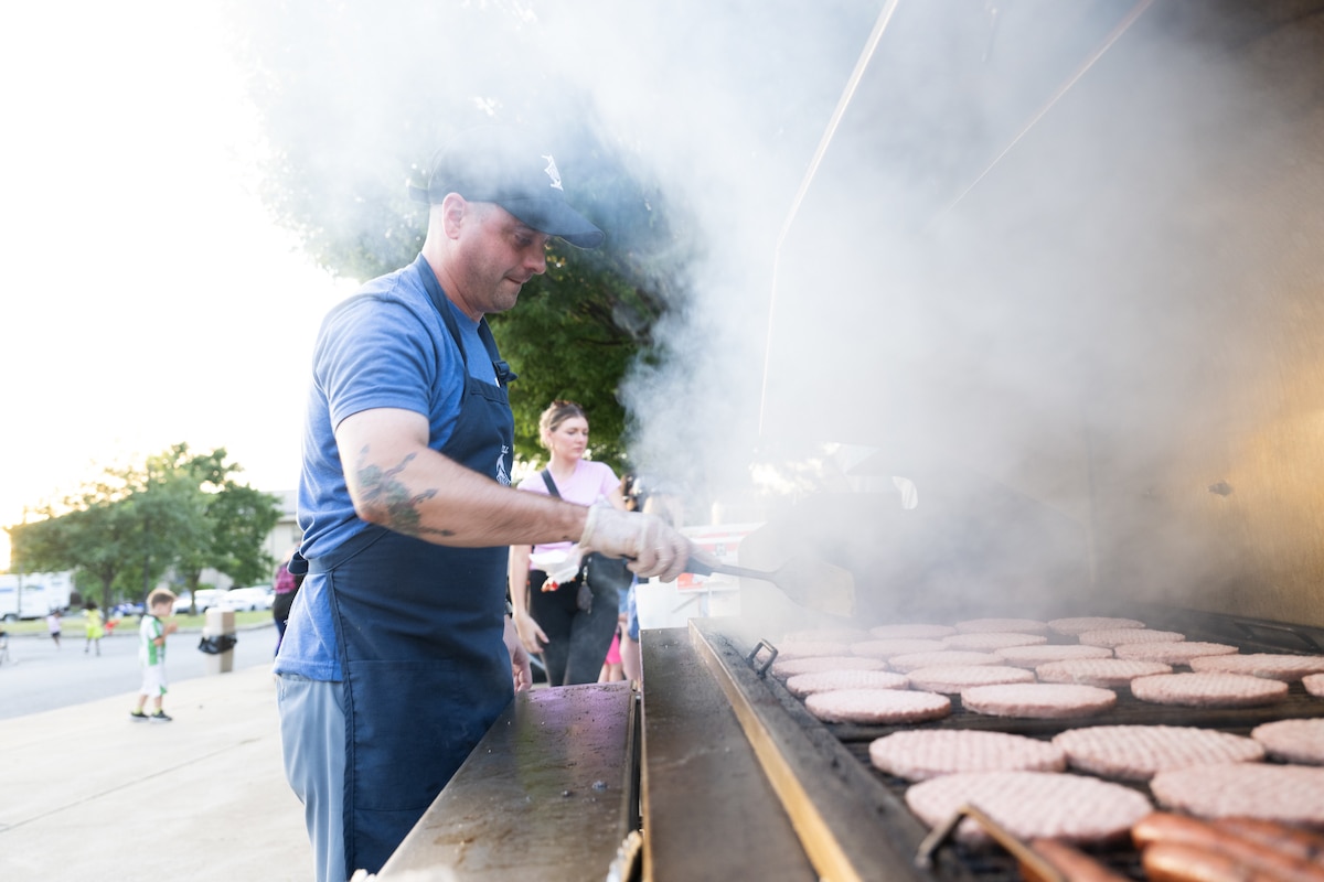 U.S. Air Force Master Sgt. Shawn Martin, 436th Security Forces Squadron first sergeant, grills hamburgers and hot dogs for attendees during the End of Summer Bash held on Dover Air Force Base, Delaware, Aug. 29, 2025. The event offered free food, live music, summer activities for children and featured information booths from seven base agencies aimed at offering support to the Dover AFB community. (U.S. Air Force photo by Mauricio Campino)