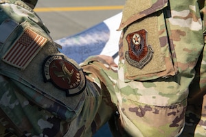 Two uniformed men with decorated patches on their sleeves point at a map.