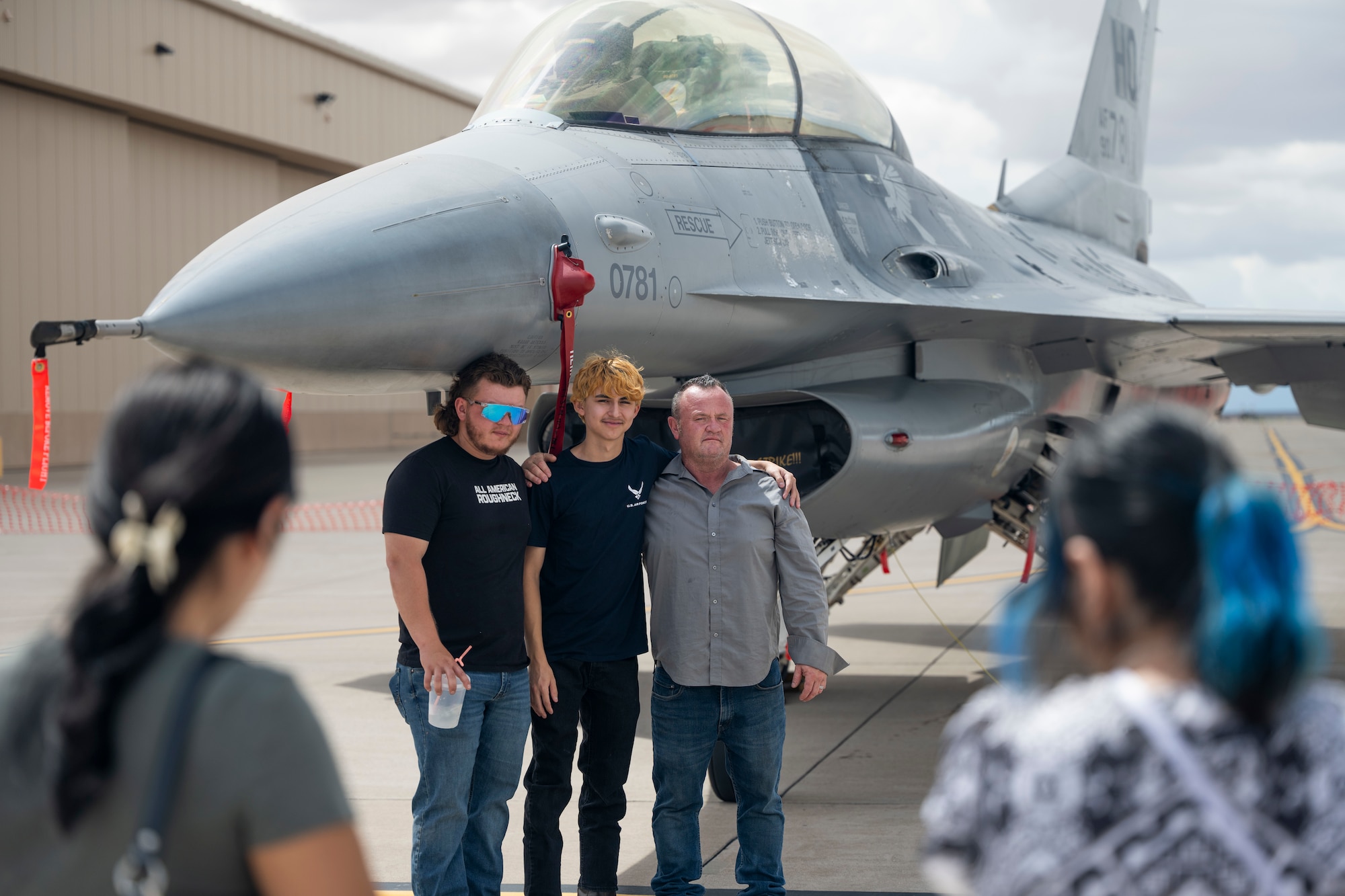 An Air Force recruit, center, poses with family in front of an F-16 Fighting Falcon during Community Connections Day at Holloman Air Force Base, New Mexico, Sept. 6, 2025. Twenty-one recruits took the oath of enlistment in front of friends, family and community members during the open house festivities of Community Connections Day. (U.S. Air Force photo by Tech. Sgt. Victor J. Caputo)
