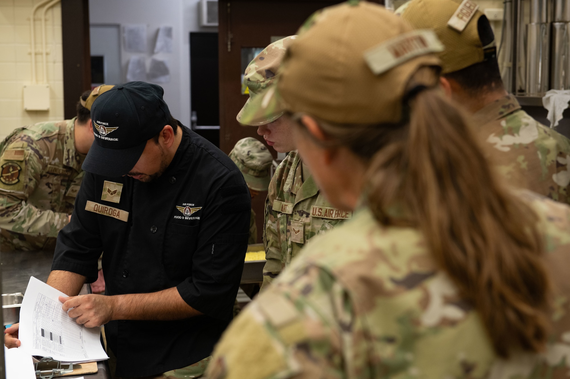 U.S. Air Force Senior Airman Fabrico Quiroga, 35th Force Support Squadron food services technician, reviews  the cooking instructions for a lunch time menu with food services Airmen assigned to the 137th Special Operations Wing, Oklahoma Air National Guard, Misawa Air Base, Japan, Aug. 13, 2025. Food services technicians focused their training to meet proper safety standards and culinary capability in order to meet overall force readiness and support objectives. (U.S. Air National Guard photo by Staff Sgt. Nicholas Swift)