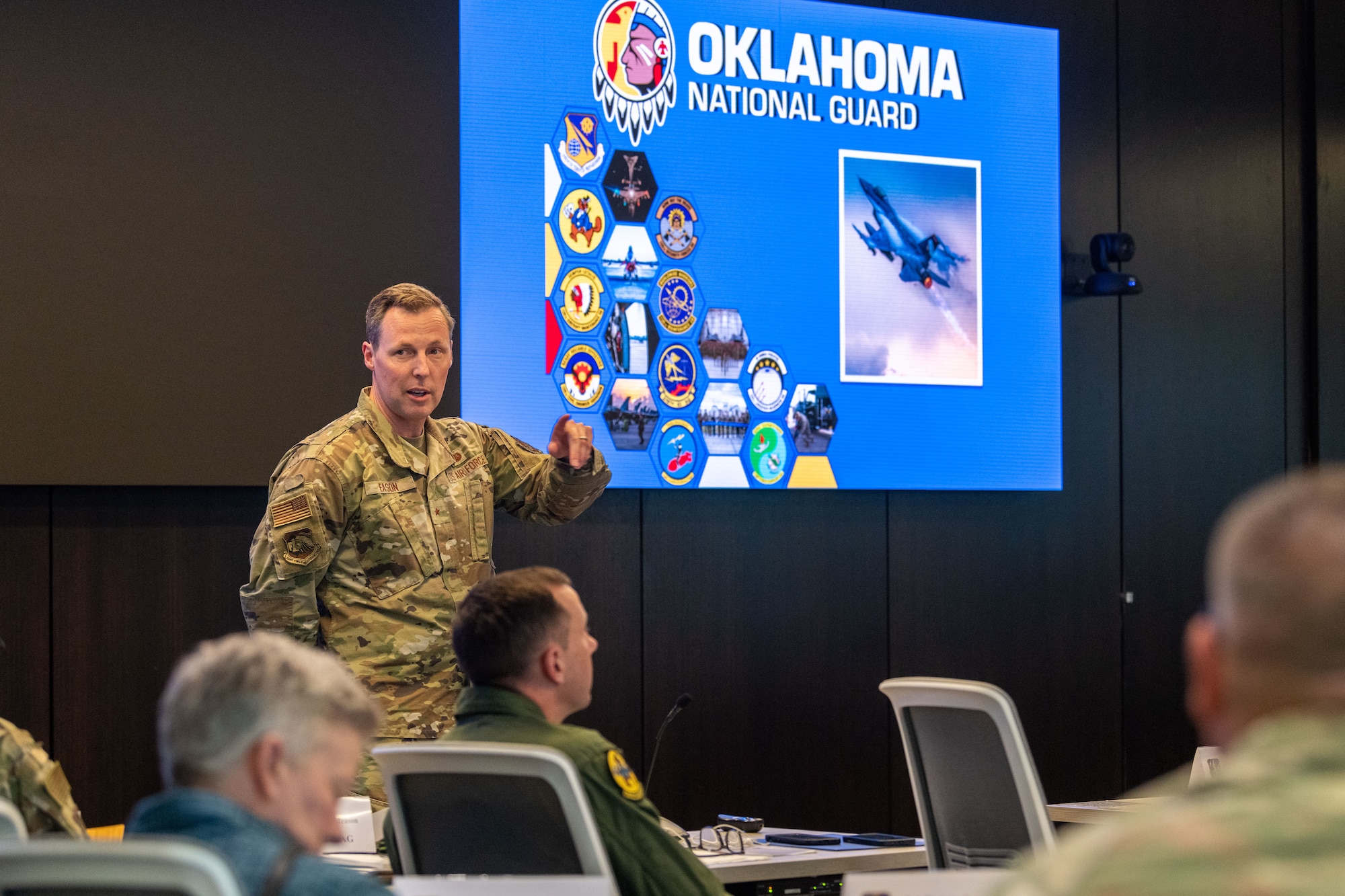 an uniformed man speaks to other uniformed military members