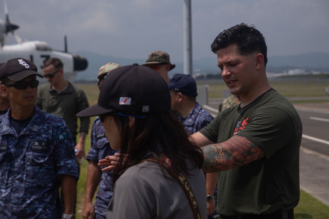 U.S. Marine Corps Staff Sgt. Ryan Cerrillo, an explosive ordnance disposal technician with Headquarters and Headquarters Squadron (H&HS) at Marine Corps Air Station Iwakuni, discusses how to examine and diffuse an improvised explosive device with members of the Japan Maritime Self-Defense Force at MCAS Iwakuni, Japan, August 26, 2025. MCAS Iwakuni EOD showed JMSDF EOD how they examine sensitive materials during a technical exchange aimed to build working relationships and to better understand each other's capabilities. (U.S. Marine Corps photo by Lance Cpl. Ella Cadby)