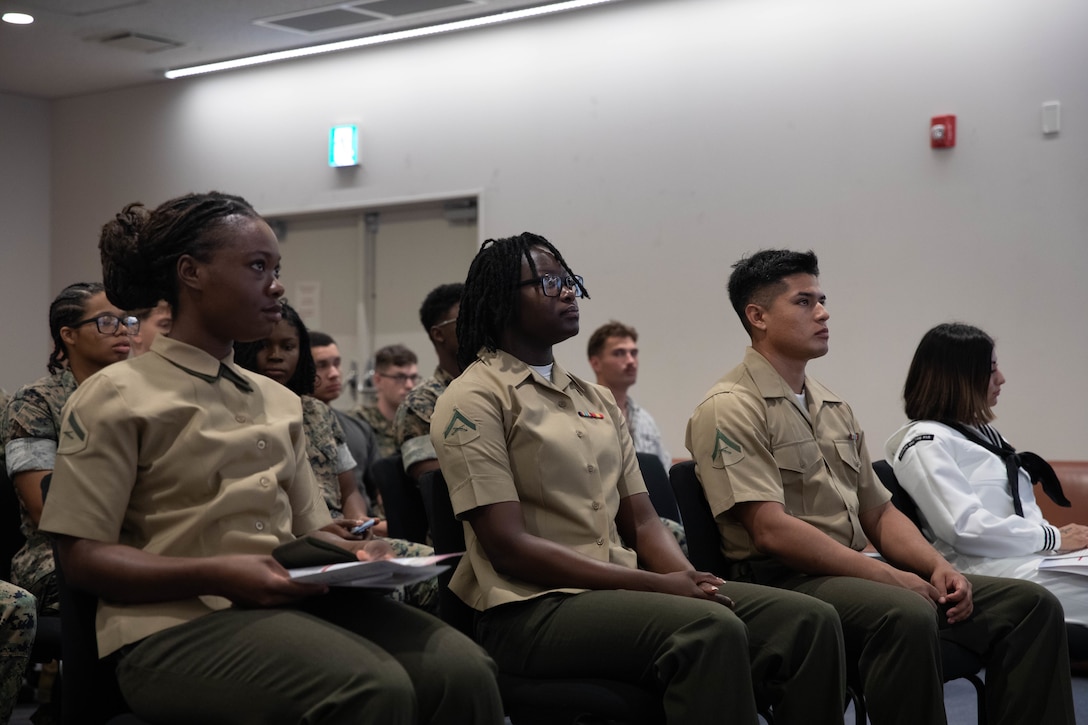 U.S. Marines and a U.S. Navy Sailor stationed at Marine Corps Air Station Iwakuni wait for a naturalization ceremony to begin at MCAS Iwakuni, Japan, Aug. 29, 2025. The naturalization ceremony was held to acknowledge military service members’ accomplishments on becoming citizens of the United States. The ceremony included service members from Haiti, Jamaica, and Peru. (U.S. Marine Corps photo by Lance Cpl. Siwan Lewis)