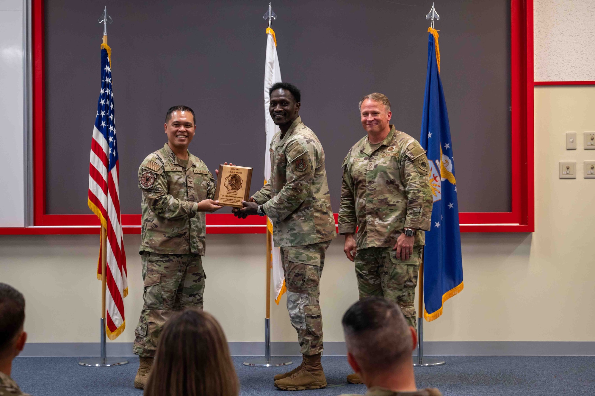 military members pose for a photo in front of a stage