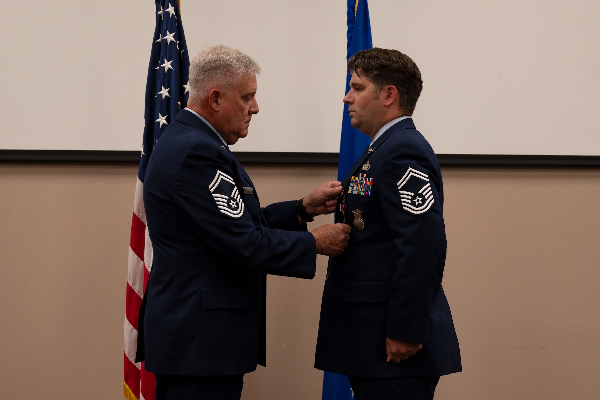 Sgt. Ganus stands while another Airman pins a ribbon onto his uniform top.