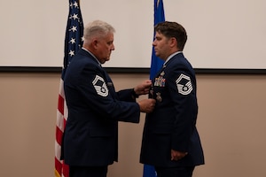 Sgt. Ganus stands while another Airman pins a ribbon onto his uniform top.