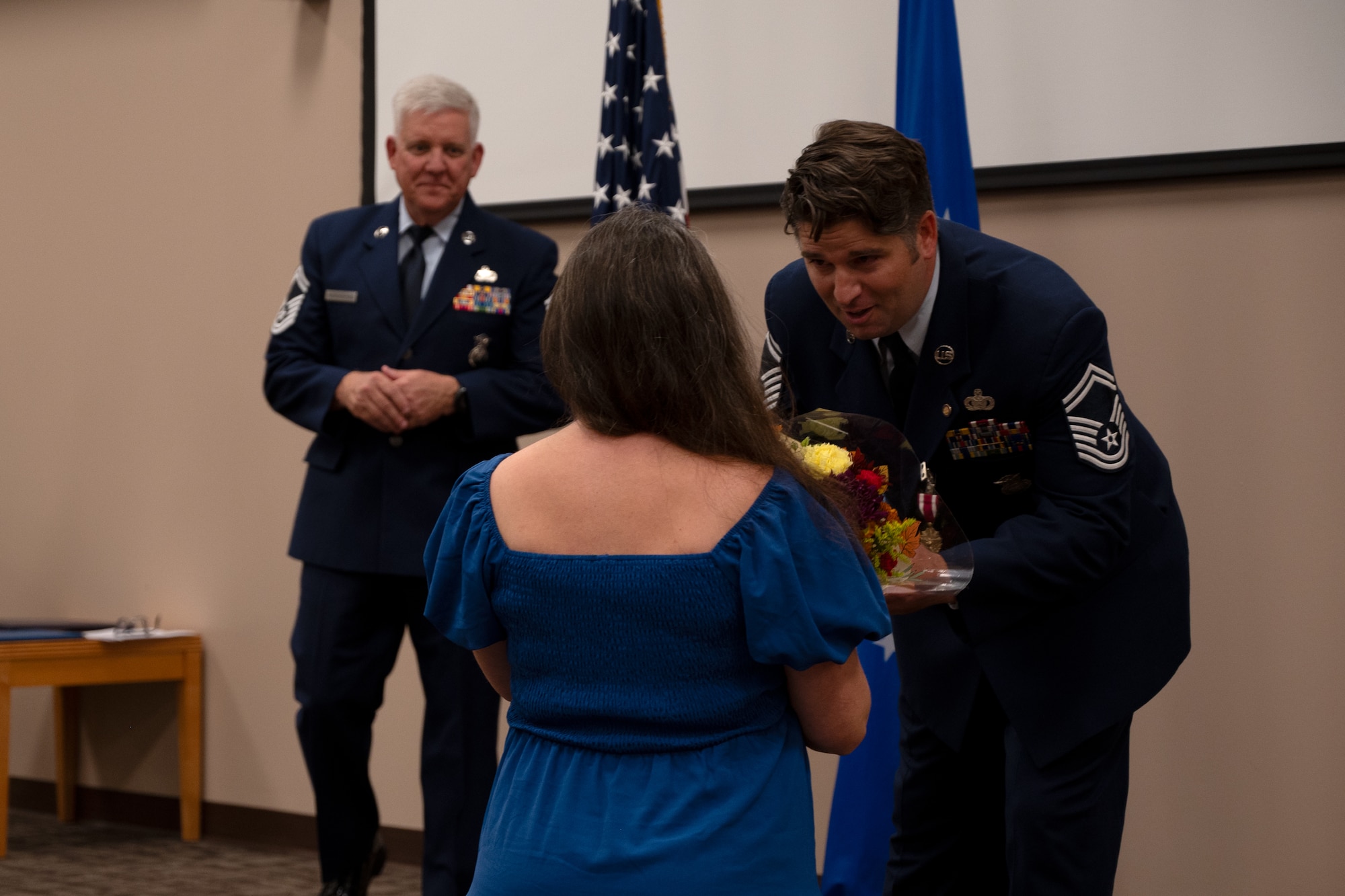 Senior Master Sgt. Ganus bends down to hand his wife a bouquet of flowers.