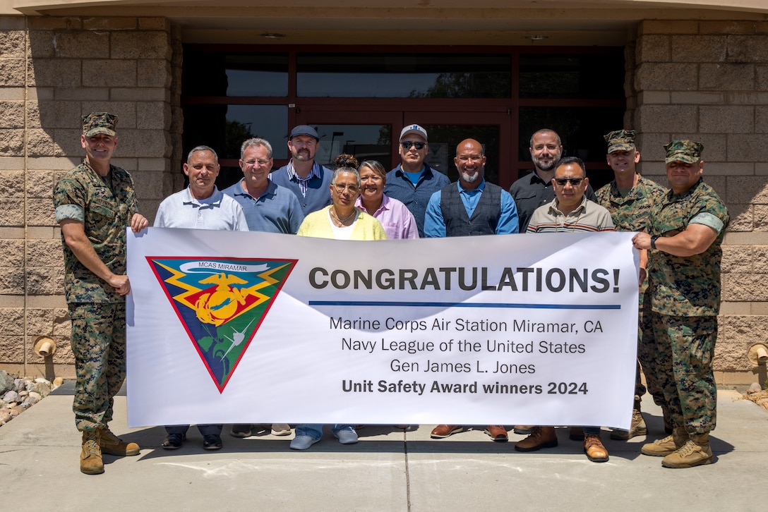 U.S. Marine Corps Col. R. Erik Herrmann, the commanding officer of Marine Corps Air Station Miramar, and Sgt. Maj. Alejandro Garcia Jr., sergeant major of MCAS Miramar, congratulate the unit safety award winners with a banner at MCAS Miramar, California, June 27, 2025. Recognition banners were presented to our outstanding Marines and civilian personnel of MCAS Miramar’s Installation Personnel Administration Center and Safety departments, reflecting their exceptional dedication and mission-focused efforts. (U.S. Marine Corps photo by Lance Cpl. Seferino Gamez)