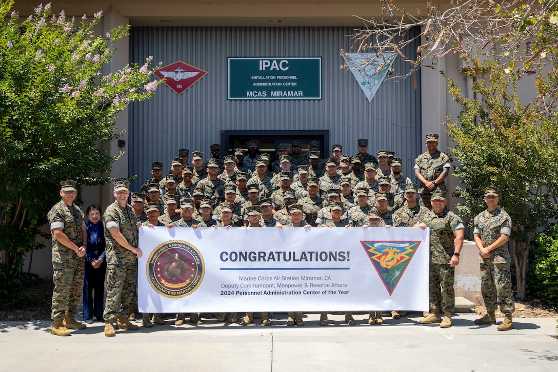 U.S. Marine Corps Col. R. Erik Herrmann, the commanding officer of Marine Corps Air Station Miramar, and Sgt. Maj. Alejandro Garcia Jr., sergeant major of MCAS Miramar, congratulate the 2024 Personnel Administration Center of the Year winners with a banner in front of the Installation Personnel Administration Center building on MCAS Miramar, California, June 27, 2025. Recognition banners were presented to our outstanding Marines and civilian personnel of MCAS Miramar’s IPAC and Safety departments, reflecting their exceptional dedication and mission-focused efforts. (U.S. Marine Corps photo by Lance Cpl. Seferino Gamez)