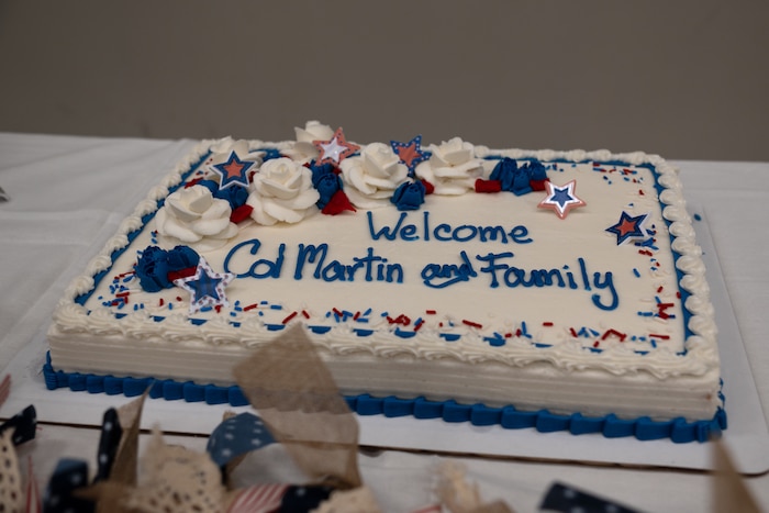 A cake that has "Welcome Col. Martin and family" written on it with blue icing.