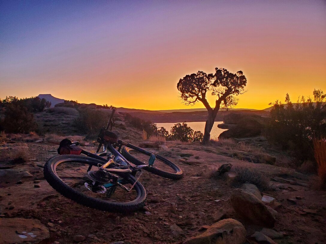 A mountain bike rests in the foreground on the mountain biking and hiking trail as the sun sets over Abiquiu Lake, Feb. 5, 2025. Photo by Samantha Jones.