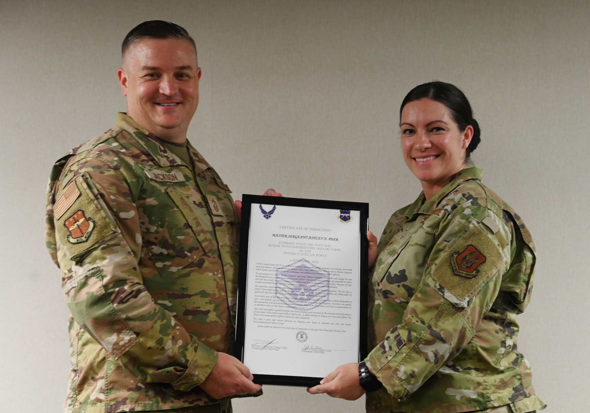 Chief Master Sgt. Jackson presents Master Sgt. Ashley Peer an induction certificate.