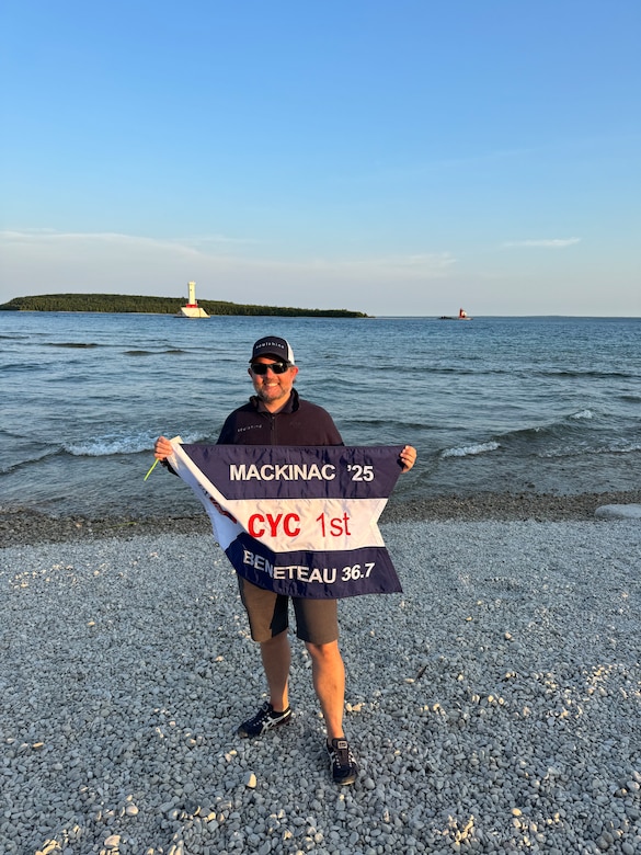 Man stands on shore displaying flag.