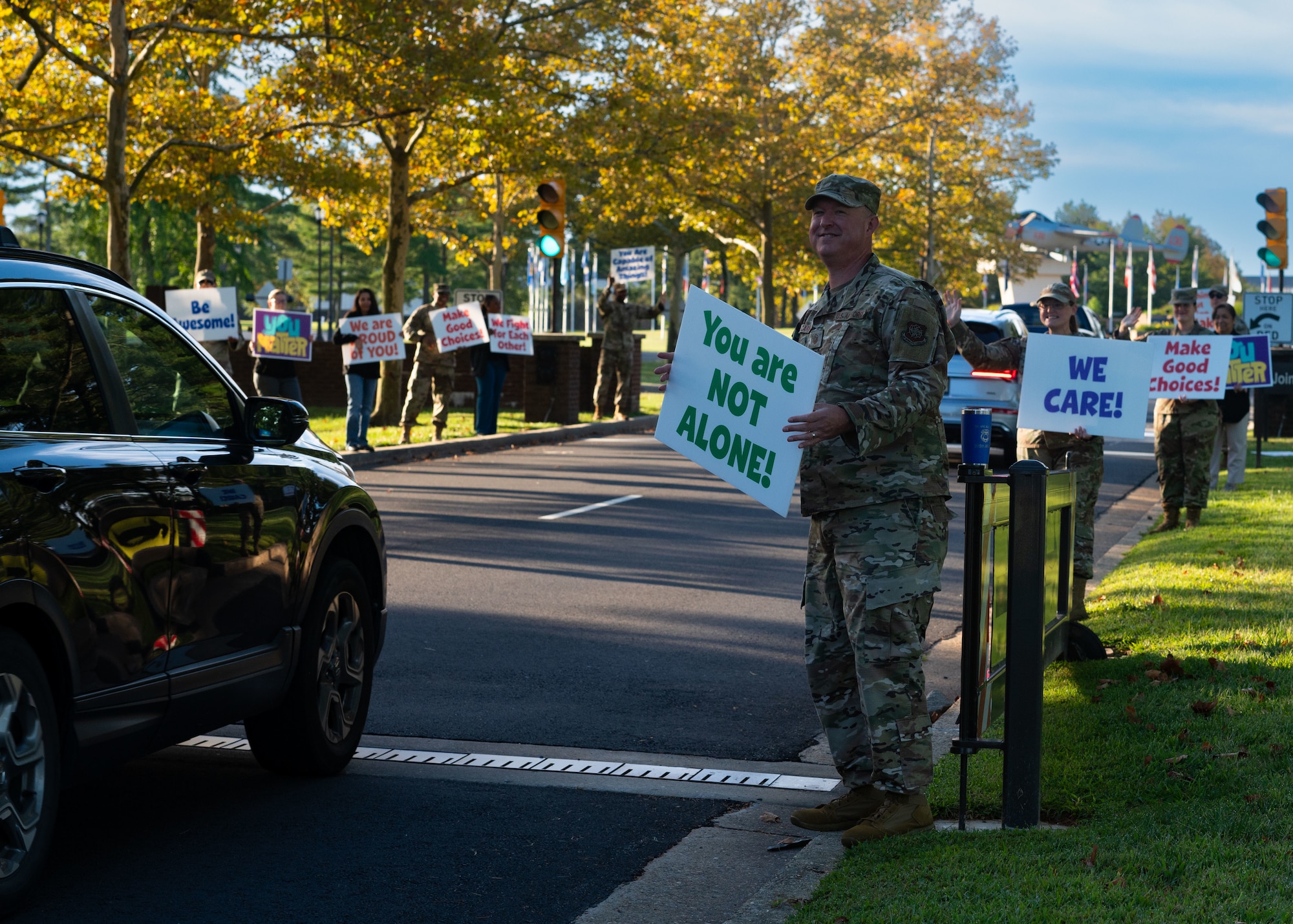 U.S. Air Force service members and Department of Defense civilians hold signs at the main gate entrance at Joint Base McGuire-Dix-Lakehurst, N.J., Sept. 8, 2025. Service members and DoD civilians held signs of encouragement for those entering the installation to raise awareness for suicide prevention.