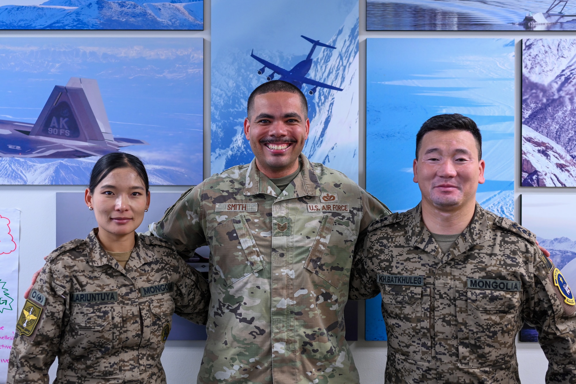 U.S. Air Force Tech. Sgt. Nolan Smith, an instructor at the Joint Base Elmendorf-Richardson  Professional Military Education Center, poses with Mongolian Air Force Sgt. Myagmarsuren Arituntuya and Senior Master Sgt. Khatanbaatar Batkhuleg on JBER, Alaska, Sept. 4, 2025. Batkhuleg and Arituntuya were among a select group from the Mongolian Air Force attending various JBER professional military education courses to study and analyze military education methods to implement and improve them in their home nation. (U.S. Air Force photo by Airman 1st Class Eli A. Rose)
