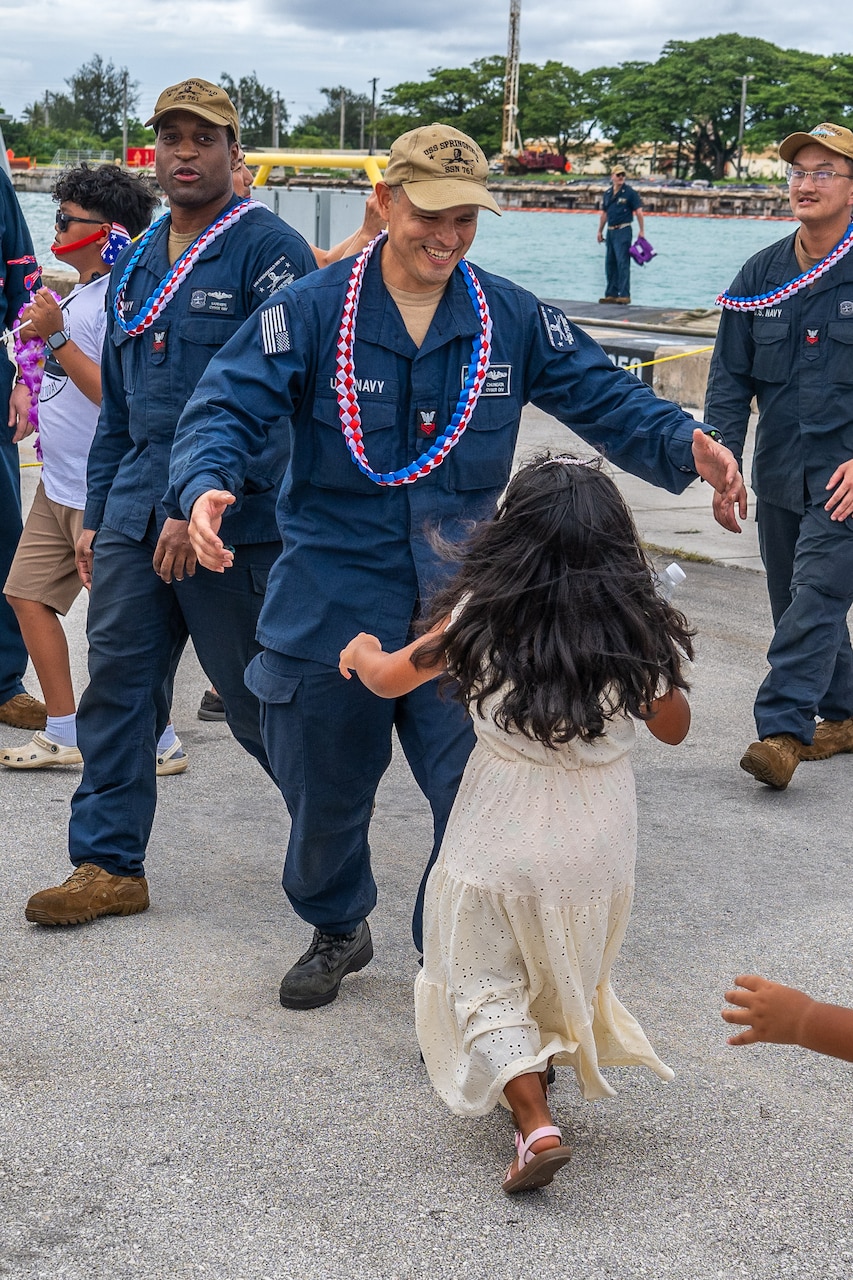 NAVAL BASE GUAM (August 31, 2025) A Sailors assigned to the Los Angeles-class fast-attack submarine USS Springfield (SSN 761) runs to greet his child, August 31, 2025. Springfield returns to its homeport at Naval Base Guam after completing a routine deployment in the Indo-Pacific. Assigned to Commander, Submarine Squadron 15, based at Polaris Point, Naval Base Guam, Springfield is one of five forward-deployed fast-attack submarines. Renowned for their unparalleled speed, endurance, stealth, and mobility, fast-attack submarines are the backbone of the Navy’s submarine force. Regarded as apex predators of the sea, Guam’s fast-attack submarines serve at the tip of the spear, helping to reaffirm the submarine force's forward-deployed presence in support of a free and open Indo-Pacific. (U.S. Navy photo by Lt. James Caliva)
