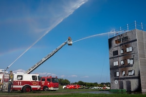 U.S Air Force firefighters spray water from a fire truck on to a simulated burning building.