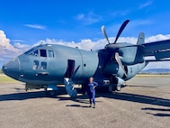 Petty Officer 2nd Class Nathalie Aviles stands with a Royal Australian Air Force C-27J Spartan airplane in Honiara, Solomon Islands, following a flight on Aug. 12, 2025.