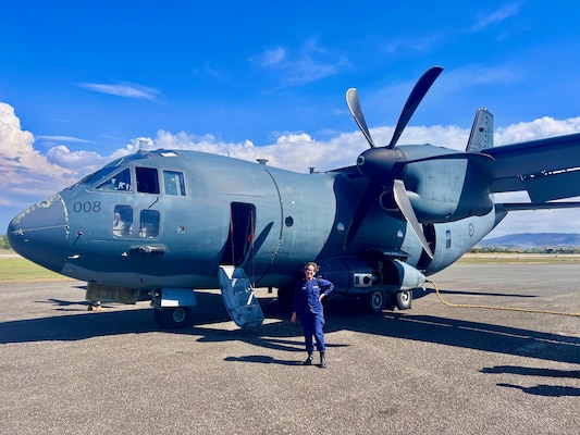 Petty Officer 2nd Class Nathalie Aviles stands with a Royal Australian Air Force C-27J Spartan airplane in Honiara, Solomon Islands, following a flight on Aug. 12, 2025.