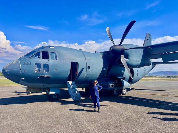 Petty Officer 2nd Class Nathalie Aviles stands with a Royal Australian Air Force C-27J Spartan airplane in Honiara, Solomon Islands, following a flight on Aug. 12, 2025.