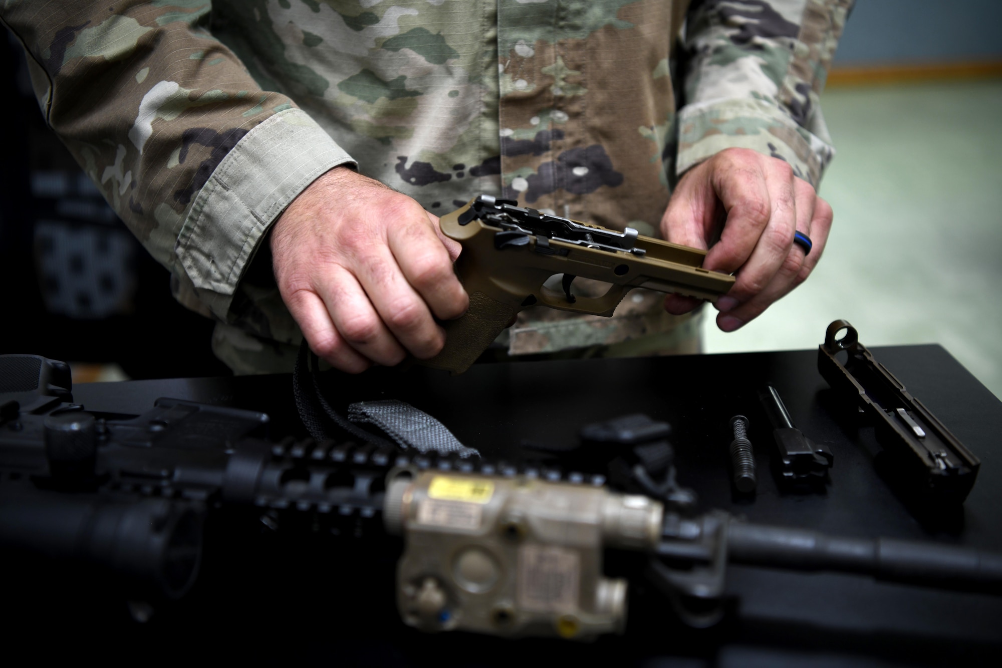 LUKE AIR FORCE BASE, Ariz. – Tech. Sgt. Steven Boatright, 944th Security Forces Squadron combat arms training and maintenance instructor, disassembles a pistol in preparation for training at Luke AFB, Ariz., Aug. 8, 2025. His experience in law enforcement and the Air Force Reserve strengthens his ability to teach Airmen critical weapons handling skills. (U.S. Air Force photo by Tech. Sgt. Tricia Topasna)