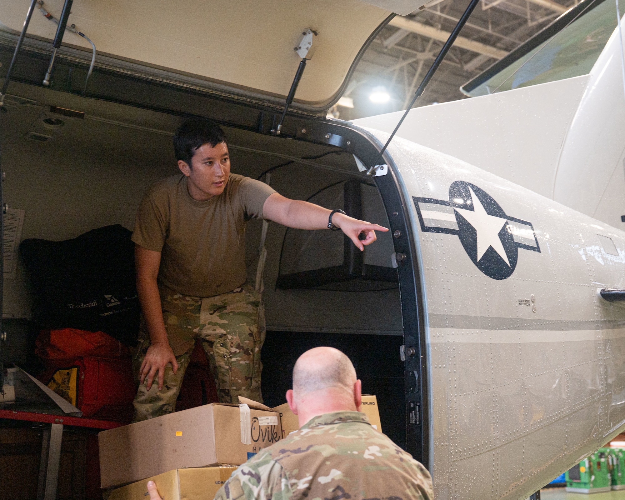 A U.S. servicemember in the back of an aircraft points offscreen