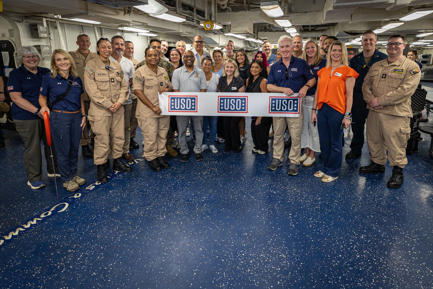 NORFOLK (July 28, 2025) Sailors assigned to the Wasp-class amphibious assault ship USS Iwo Jima (LHD 7) and United Service Organization (USO) staff take a group photo during a ribbon cutting ceremony. The event acknowledges the grand opening of the first USO ship-based recharge centers on an amphibious assault ship. Iwo Jima is the flagship of the Iwo Jima Amphibious Ready Group (ARG) which is capable of conducting global missions to accomplish U.S. strategic goals, deter adversaries, and ensure unimpeded commerce by keeping the high seas open and free in accordance with international law. Embarked aboard ARG shipping is the 22nd MEU (SOC) and provides a forward-deployed, flexible sea-based Marine Air Ground Task Force (MAGTF) capable of conducting amphibious operations—to include enabling the introduction of follow-on forces and designated special operations to meet Combatant Commander’s requirements. (U.S. Navy photo by Mass Communication Specialist 1st Class Erickson B. Magno)