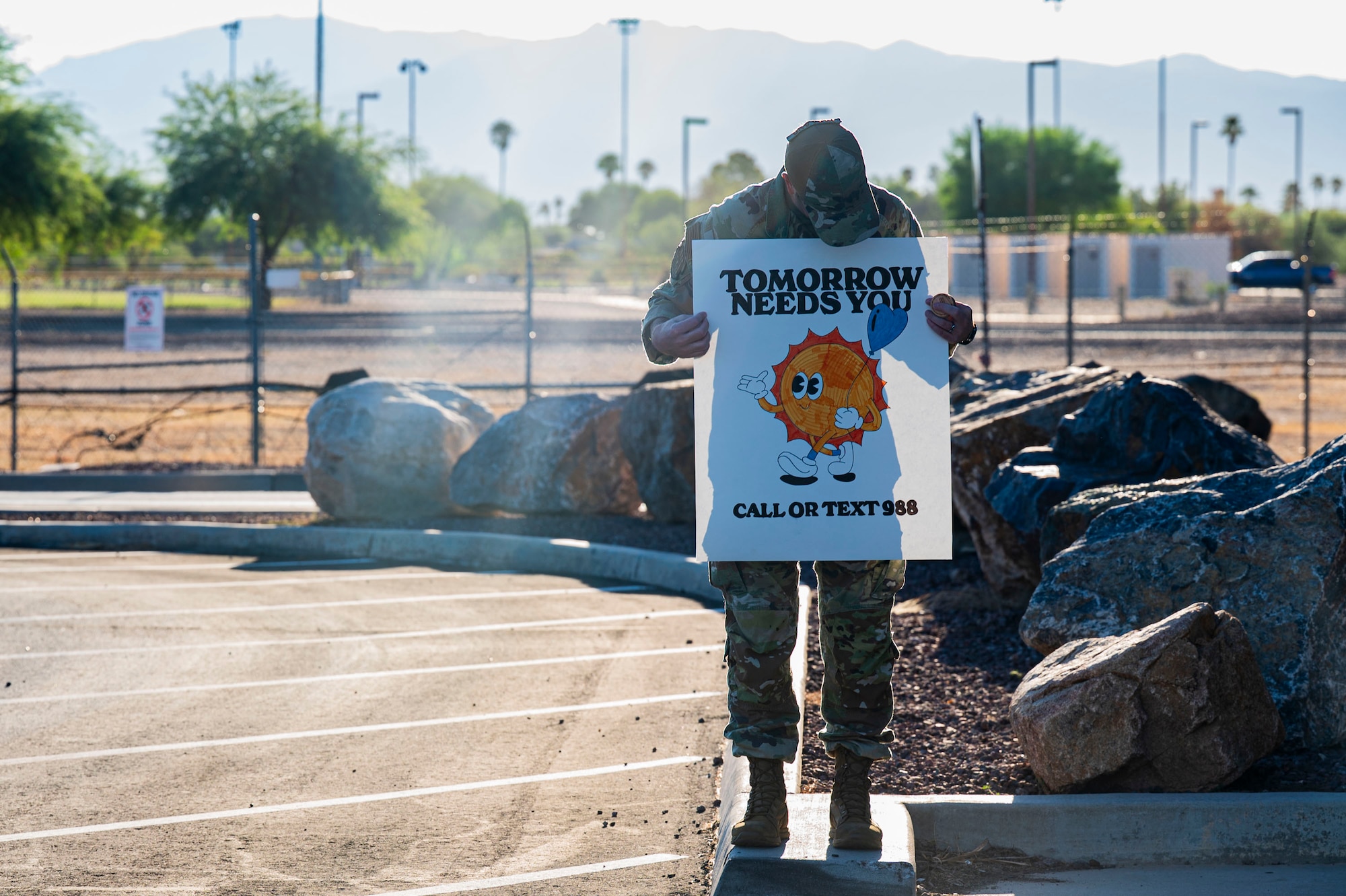 U.S. Air Force Master Sgt. Keith Holland, 25th Operational Weather Squadron first sergeant, holds a sign for drivers entering Davis-Monthan Air Force Base, Arizona, Sept. 8, 2025. The encouraging words displayed on the signs reminded Airmen and families of the strength found in seeking help. (U.S. Air Force photo by Airman 1st Class Samantha Melecio)