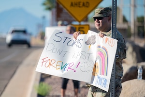 U.S. Air Force Master Sgt. Marco Coronel, Integrated Resilience superintendent, holds a sign for drivers entering Davis-Monthan Air Force Base, Arizona, Sept. 8, 2025. The initiative was part of DM’s ongoing efforts to strengthen resilience and prevent suicide within the Air Force community. (U.S. Air Force photo by Airman 1st Class Samantha Melecio)