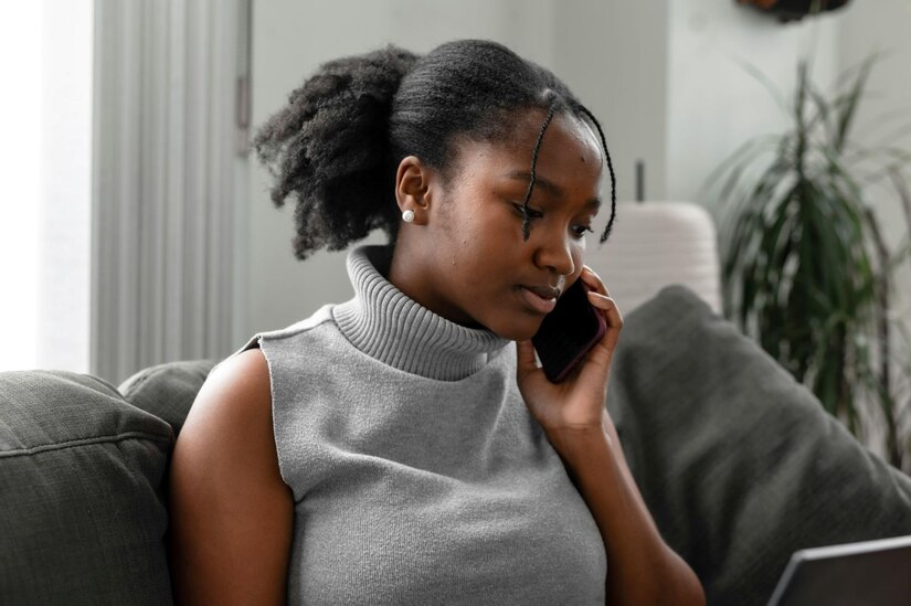 Young woman sitting on couch speaking on cell phone