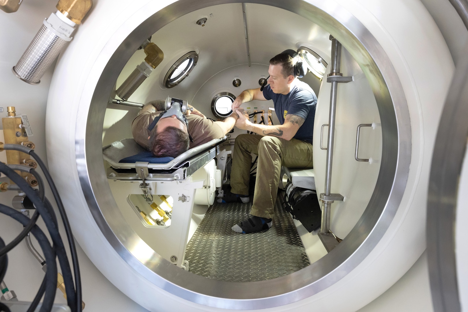 Navy Diver 1st Class Josh Amberson, right, and Navy Diver 2nd Class Hale Gage conduct a simulated emergency inside the new hyperbaric chamber, July 29, 2025, at Naval Base Kitsap-Bangor, Washington. (U.S. Navy photo by Wendy Hallmark)