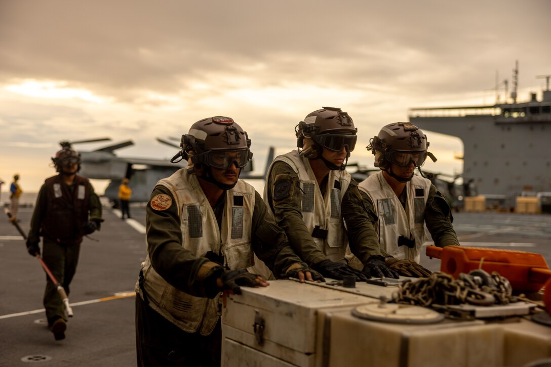 U.S. Marines with Marine Medium Tiltrotor Squadron (VMM) 363, Marine Rotational Force – Darwin 25.3, push a corrosion control cart during flight deck operations for MV-22B Ospreys with U.S. Navy Sailors aboard the expeditionary sea base USS Miguel Keith (ESB 5) in the Philippine Sea, Aug. 29, 2025. For the first time in the rotation’s history, the MRF-D Marine Air-Ground Task Force's Aviation and Ground Combat Elements embarked aboard a U.S. Navy vessel to extend operational reach and provide flexible, combat-credible options across the Indo-Pacific. MRF-D is an annual six-month rotational deployment to enhance interoperability with the Australian Defence Force and allies and partners and provide a forward postured crisis response force in the Indo-Pacific. (U.S. Marine Corps photo by Cpl. Angelina Sara)