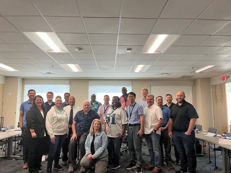 A group of men and women pose for a picture in a conference room.