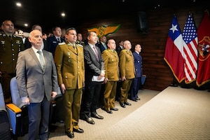 Senior leaders from Carabineros de Chile, the U.S. Embassy in Santiago, and U.S. and Chilean military organizations stand for the national anthems during the inaugural International Seminar on Operational Safety and Countering the Use of Unmanned Aerial Systems at the Carabineros Air Prefecture.