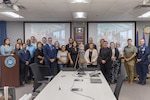 A group photo of men and women surrounded by a plaque