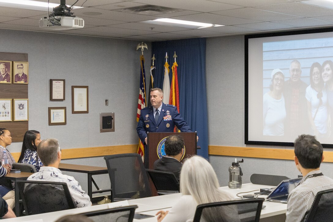 A man in a blue military uniform stands at the podium