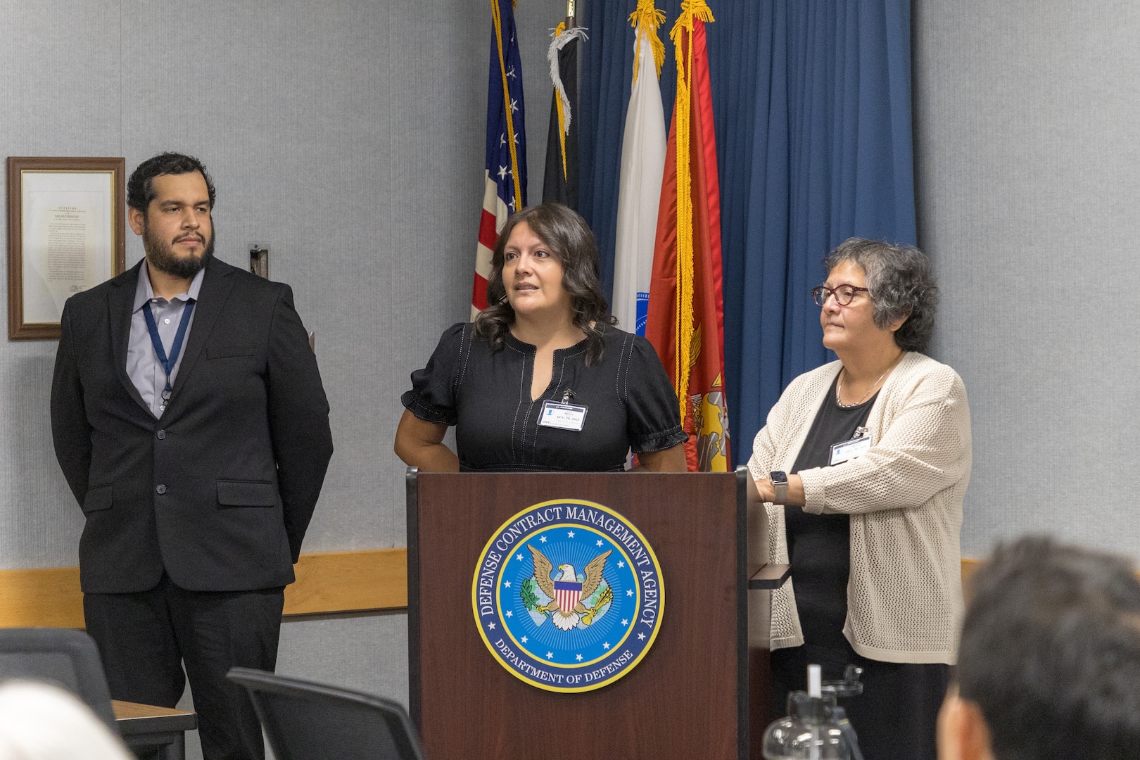A man and two women stand at a podium