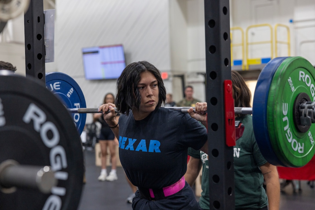 U.S. Marine Corps Staff Sgt. Kaitlynn Remy, a legal chief assigned to Marine Wing Headquarters Squadron 2, performs a barbell squat during a Semper Fit High Intensity Tactical Training Program powerlifting competition at Marine Corps Air Station Cherry Point, North Carolina, Aug. 22, 2025. The HITT Program provides Marines with elite resources, experts, events and competitions to sustain physical combat readiness. The six awarded winners were chosen based off of the total weight lifted in comparison to their body weight. (U.S. Marine Corps photo by Lance Cpl. Naimah Green)